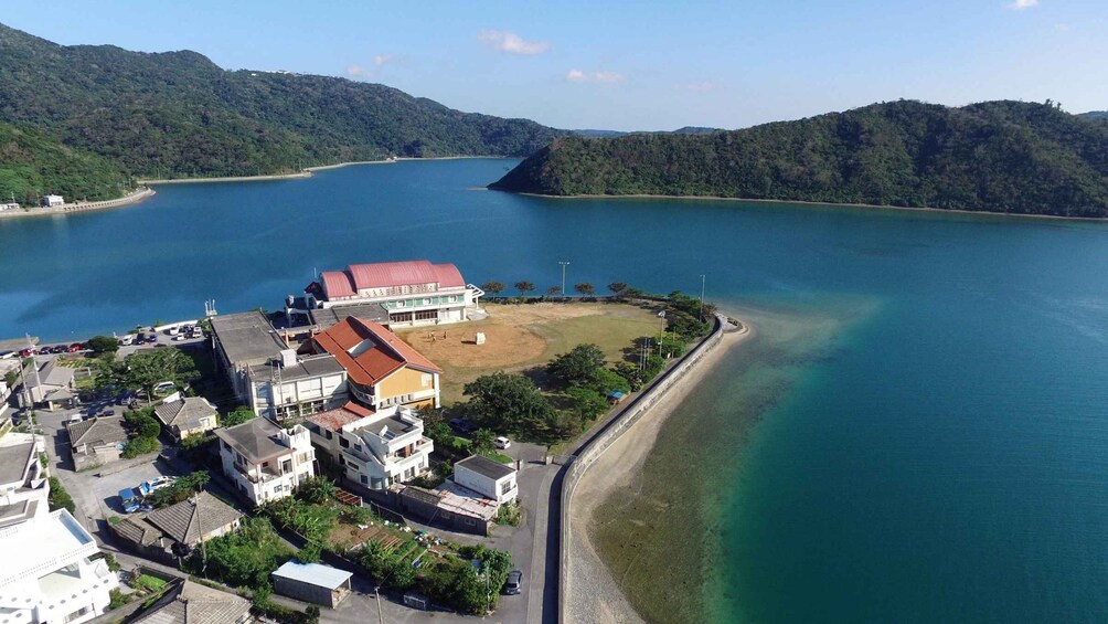 A coastal town with buildings near a large body of water, surrounded by hills. 2