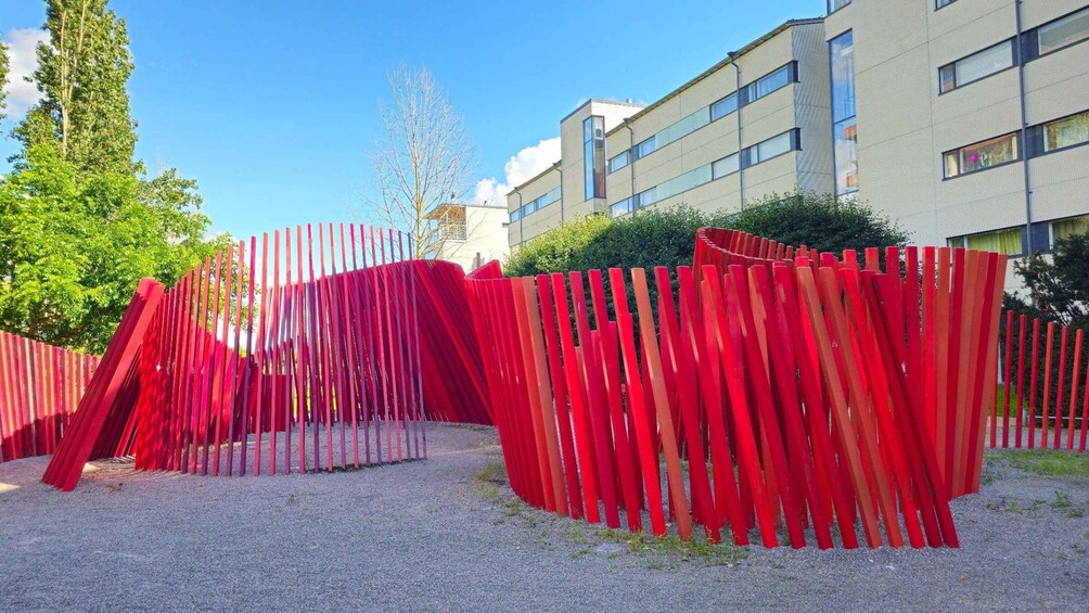A red fence with a unique design, a building in the background, and a clear blue sky. 5