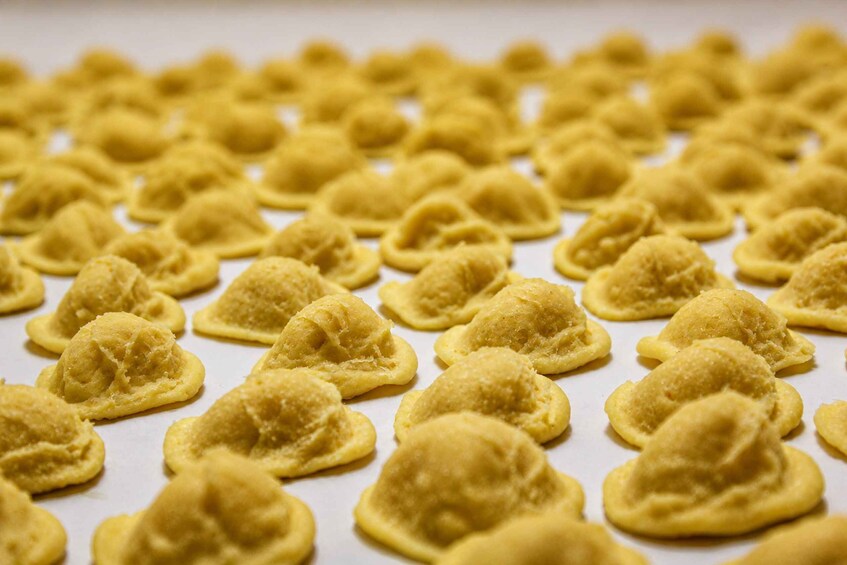 A tray of golden-brown ravioli arranged neatly on parchment paper. 1