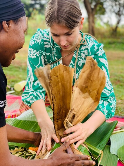 Two people preparing food with banana leaves. 3