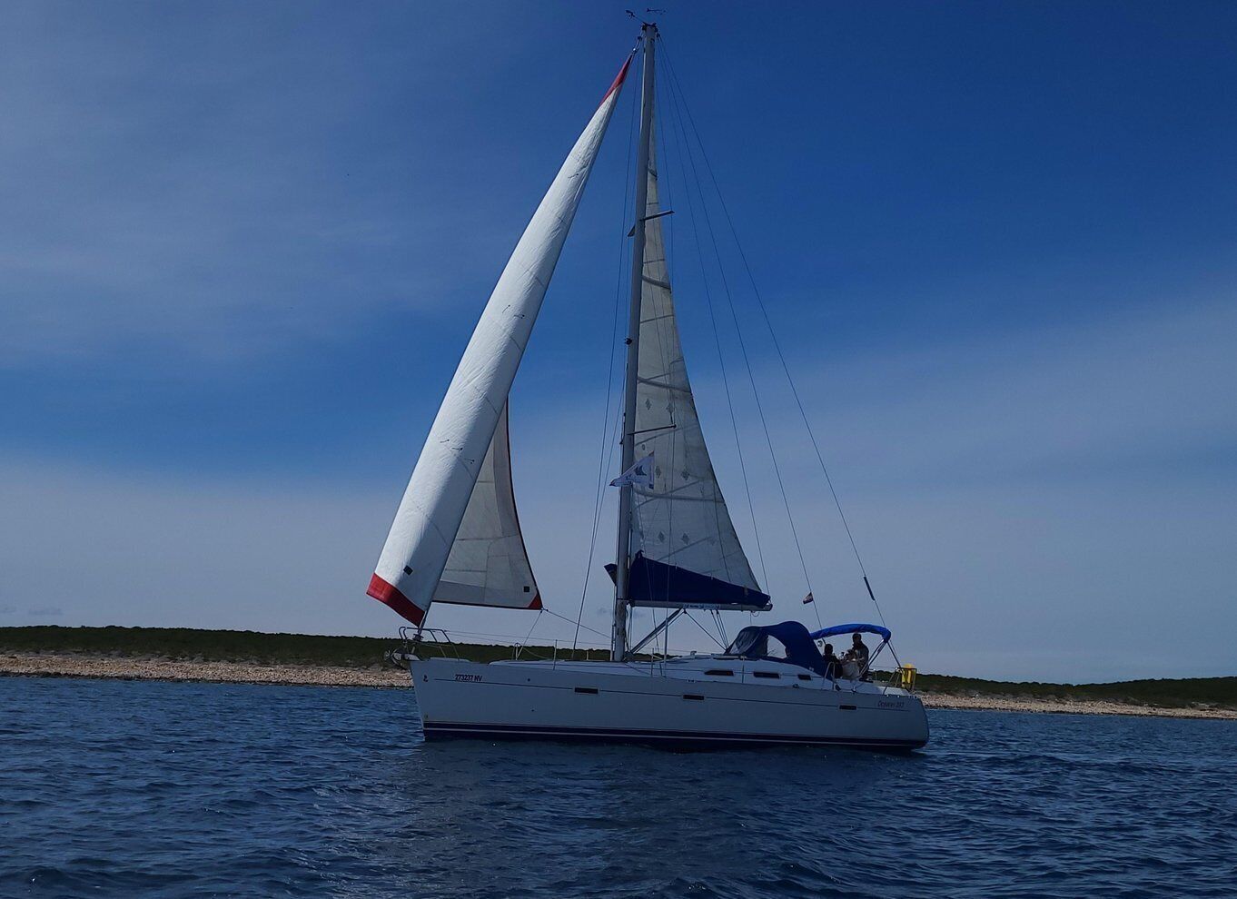 A sailboat with a white hull and red and white sails on calm water. 4