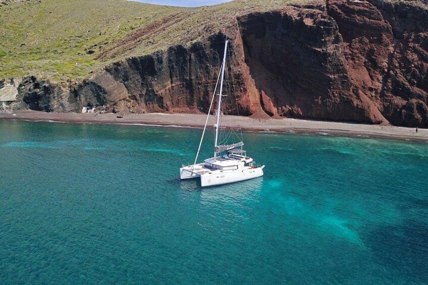 A white sailboat anchored in clear turquoise waters with a rocky coastline in the background. 5