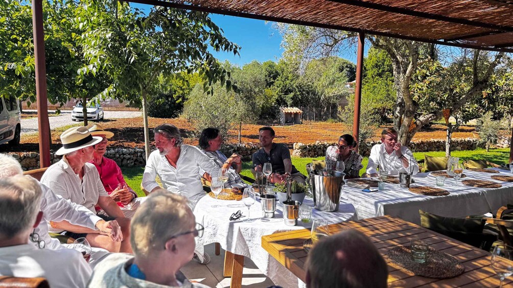 A group of people seated at tables outdoors, engaged in conversation. 1