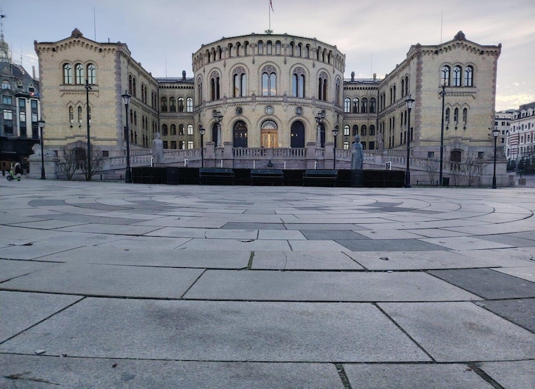 Suuri, historiallinen rakennus, jossa on kaarevat ikkunat ja keskeinen kupoli. Rakennuksen ympärillä on tilava aukio, jonka pinta on koristeltu kuvioiduilla kivilaatoilla. 1