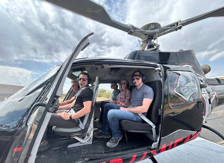 A helicopter with four passengers inside, parked outdoors. 5