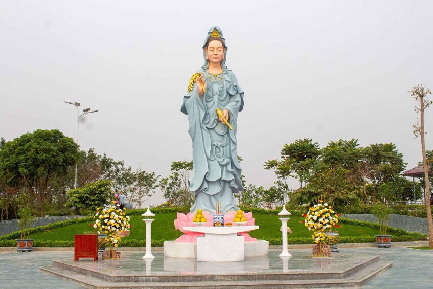 A large statue of a robed figure with a golden object, surrounded by lotus flowers and incense burners. 4