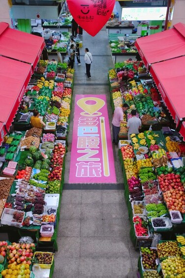 An indoor market with a central aisle marked by a pink sign with Chinese characters. 2