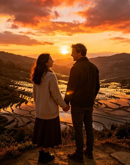 A couple holding hands overlooking terraced fields at sunset. 3