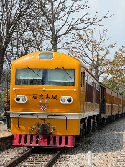 A yellow train with Chinese characters on the front, traveling on tracks. 5