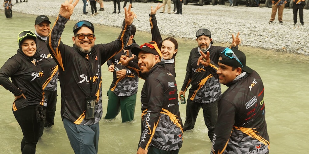 A group of people in wetsuits celebrating near a body of water. 5