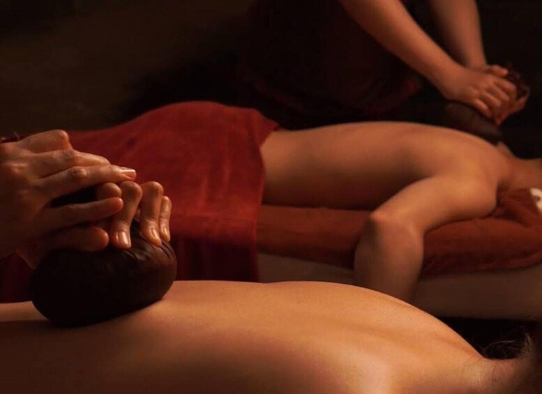 A massage session with a person lying face down and another person applying pressure with their hands. 4