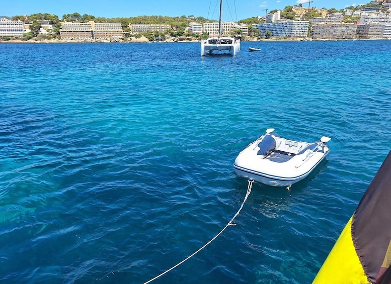 A small boat anchored in clear blue water with a cityscape in the background. 5