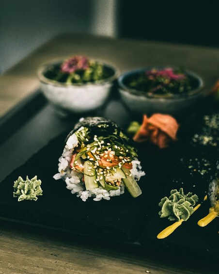 A sushi dish with rice, cucumber, and salmon on a black plate. 1