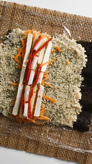 A sushi roll with vegetables on a bamboo mat. 5