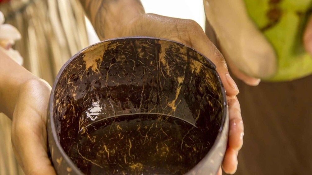 A person holding a dark bowl with gold patterns. 3