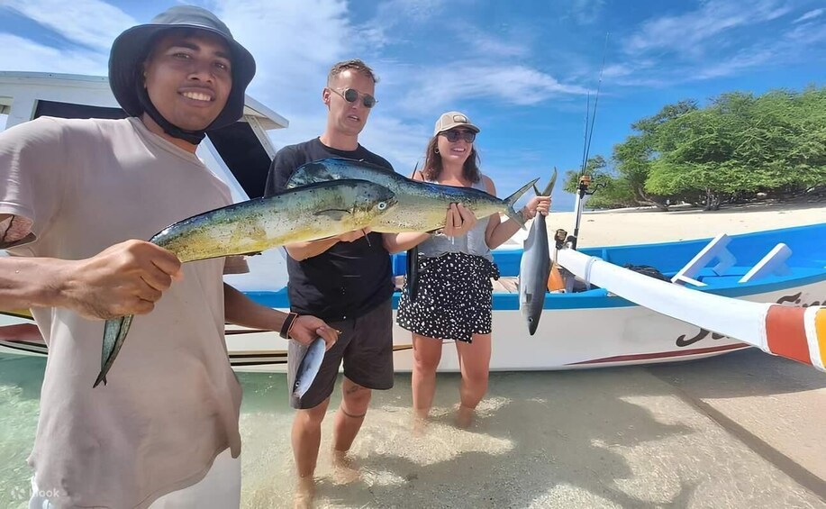 Three people holding fish on a boat near a beach. 4