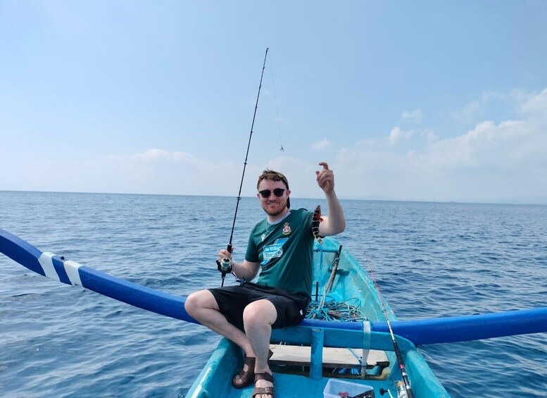 A person sitting in a boat on the water, holding a fishing rod. 5