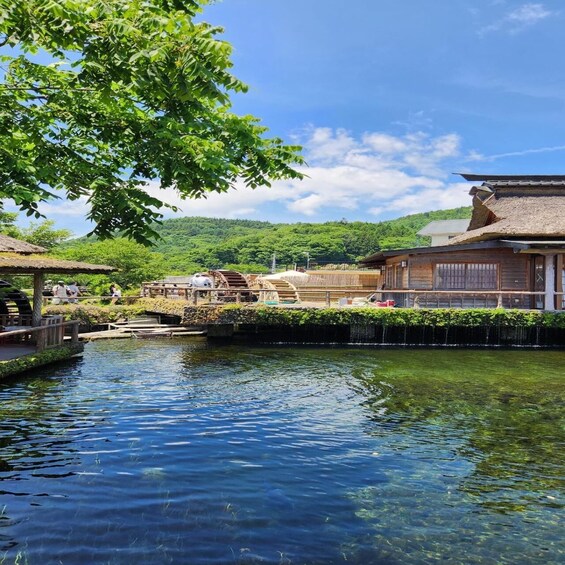 A calm river with traditional wooden structures, a thatched-roof building, and a bridge. 3
