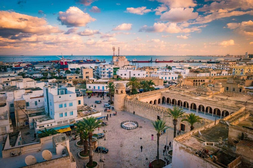 A coastal cityscape with a prominent windmill, a central square, and historic buildings. 2