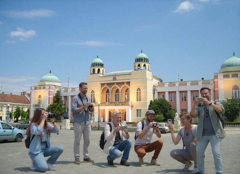 A group of people taking photos in front of a historic building with domed towers. 3