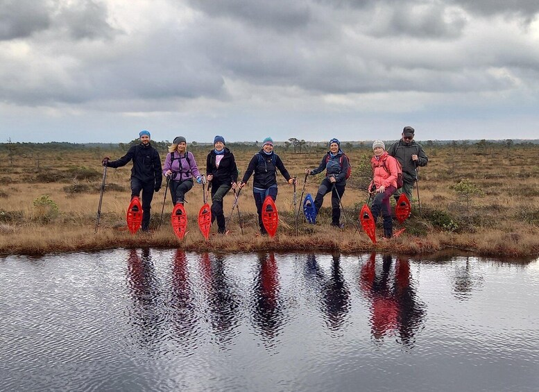 A group of people in outdoor gear standing by a body of water with red flotation devices. 3