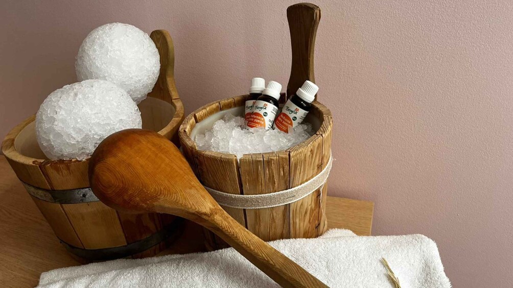 A wooden bucket filled with ice, a wooden spoon, and bottles of essential oils. 2