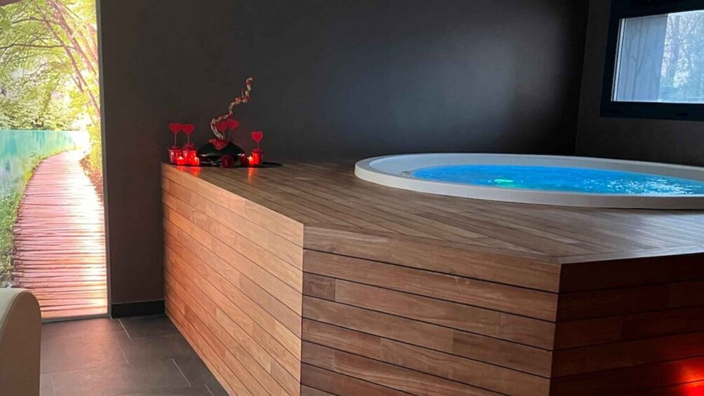 A wooden spa area with a hot tub, a wooden bench, and a pathway leading outside. 5