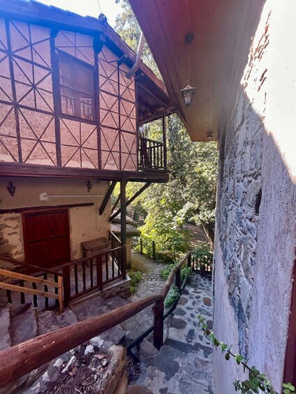 A traditional wooden house with a balcony, a stone staircase, and a wooden fence. 2