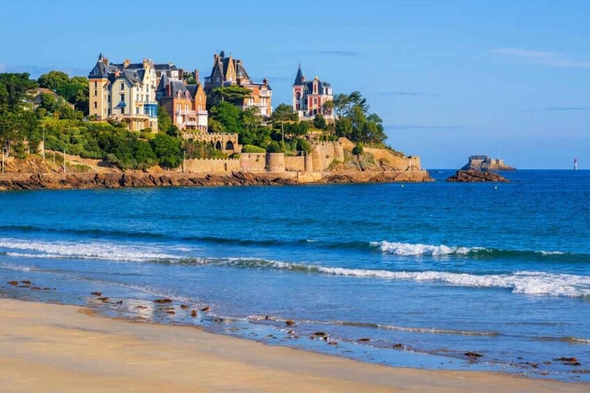 A coastal town with historic buildings, a fort, and a clear blue sea. 5