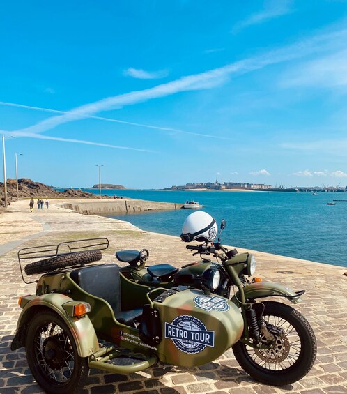 A vintage motorcycle with a sidecar parked on a stone waterfront. 3