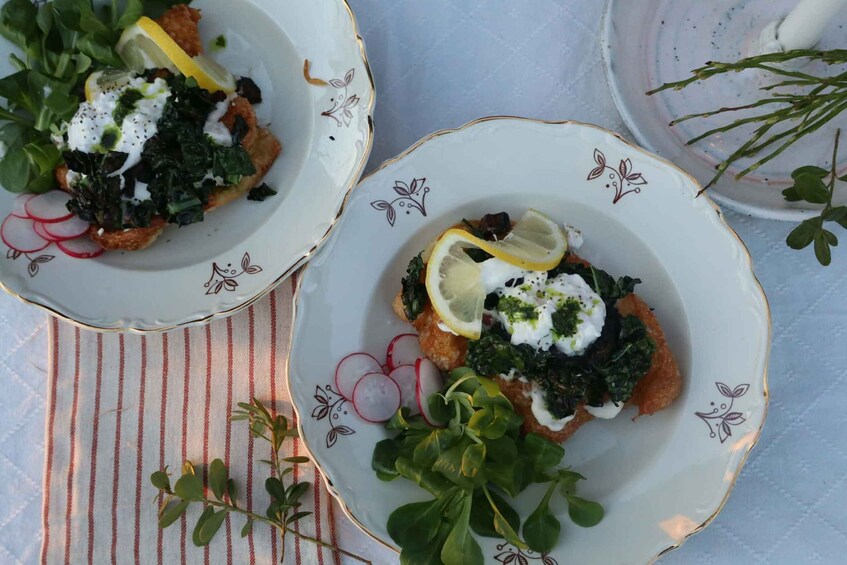 Two plates of food with greens, radishes, and lemon slices. 2