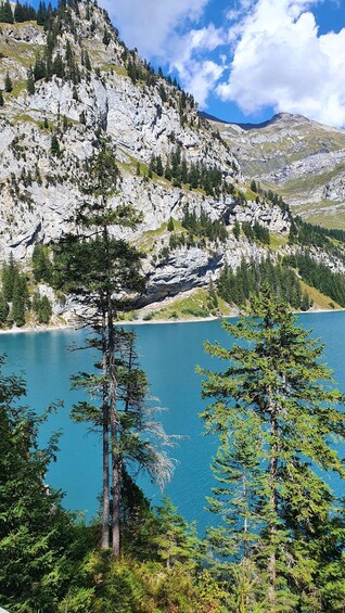 A mountainous landscape with a clear lake, rocky cliffs, and coniferous trees. 1