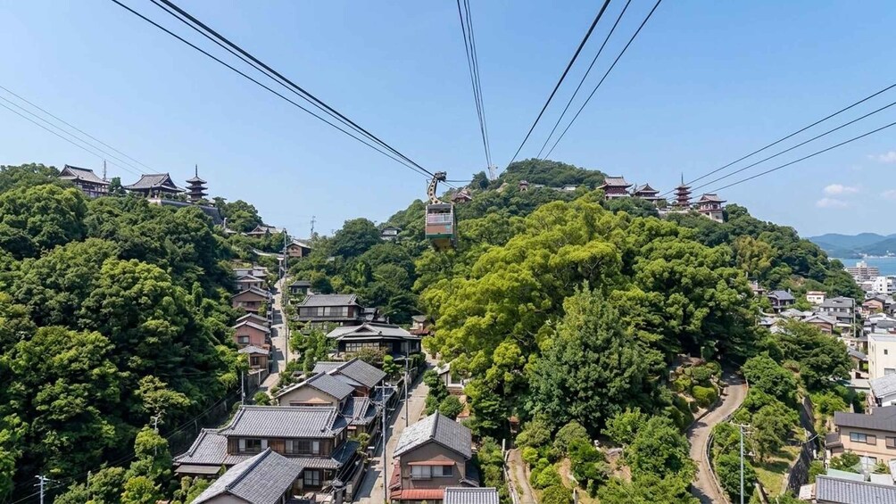 A cable car system, traditional Japanese buildings, and lush greenery on a hillside. 3
