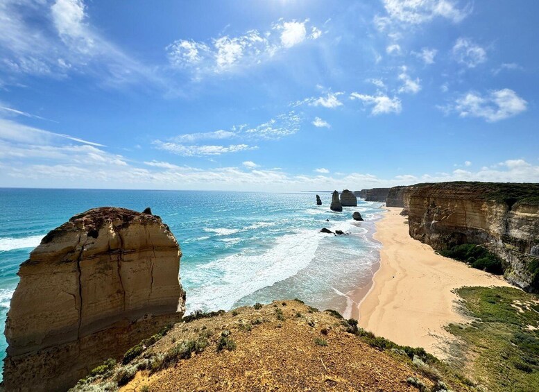 A coastal landscape with cliffs, a sandy beach, and the ocean. 1