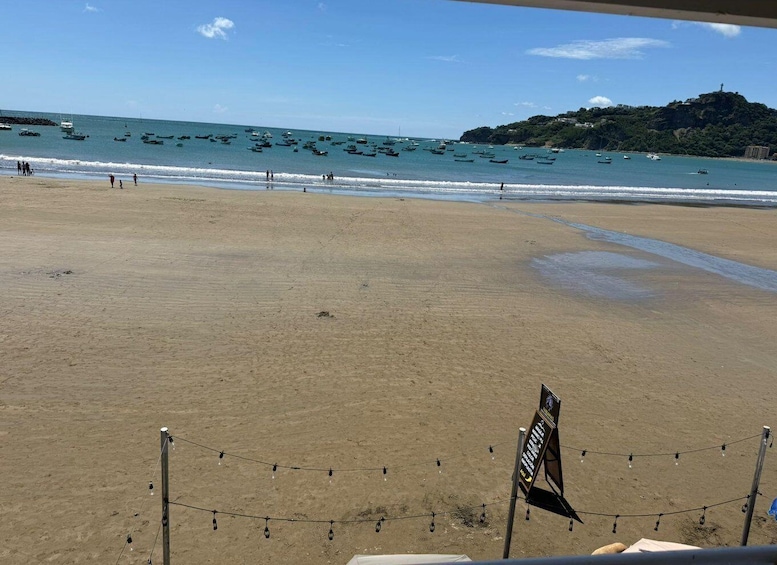 A beach with a clear sky, calm sea, and a distant hill with a statue. 4