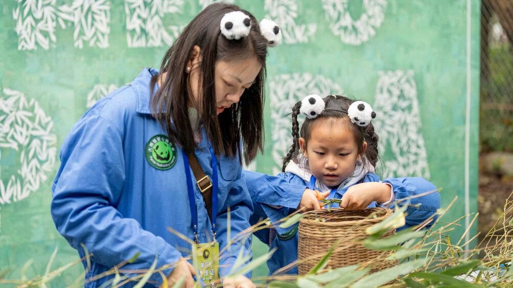 A person in a blue jacket with a panda headband interacting with a child in a similar outfit, both examining a woven basket. 5