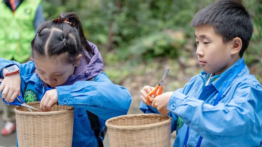 Two children in blue raincoats cutting paper with scissors. 3