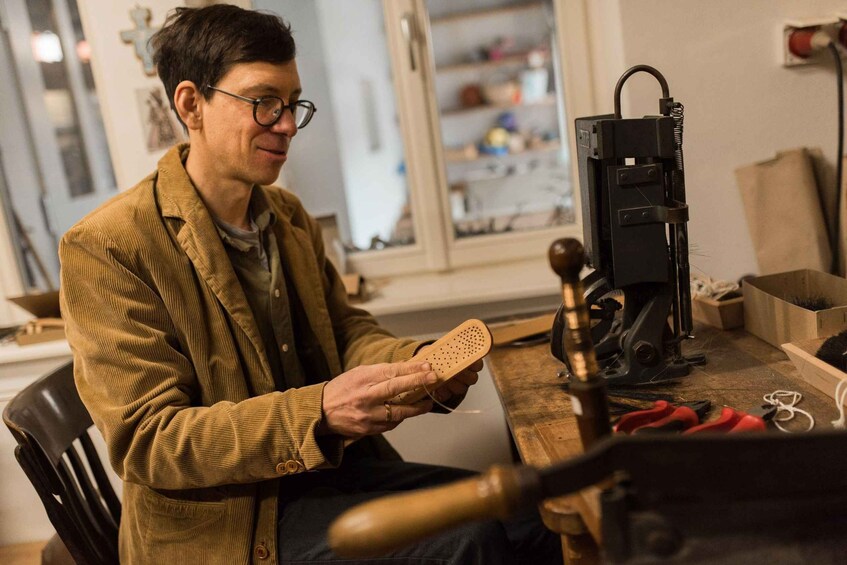 A person holding a wooden object, working at a desk with a vise and tools. 1
