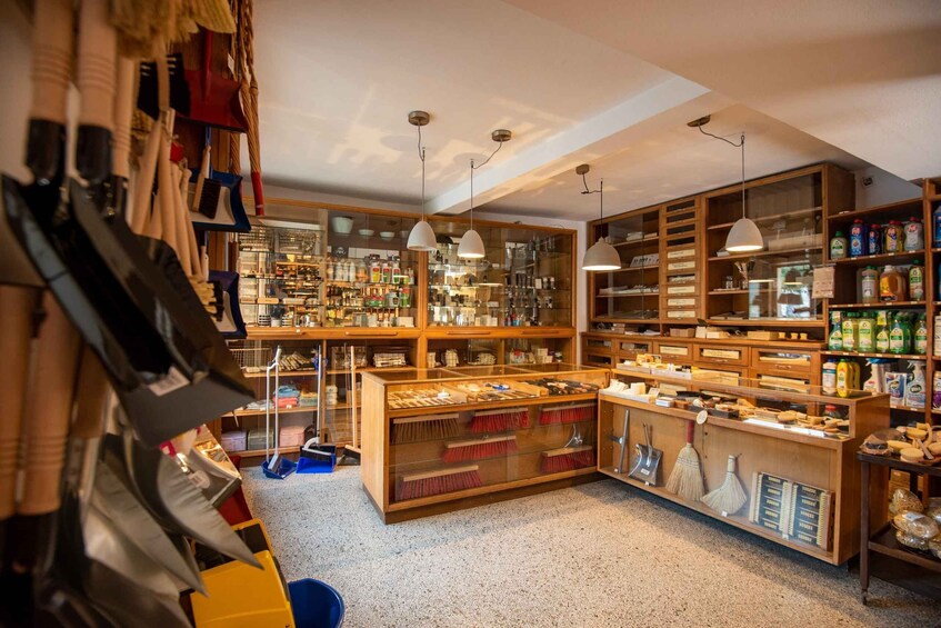 A well-organized store with wooden shelves, various cleaning supplies, and hanging brooms. 5