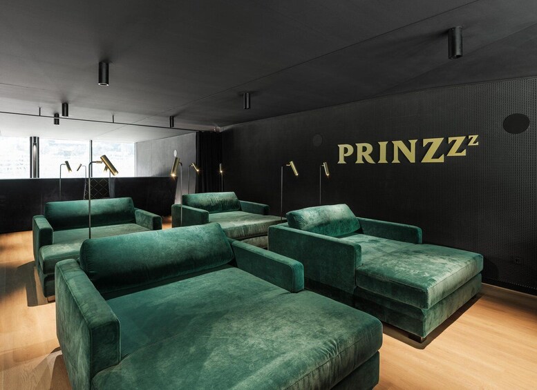 A modern lounge with green sofas and a wall with 'PRINZZ' signage. 5