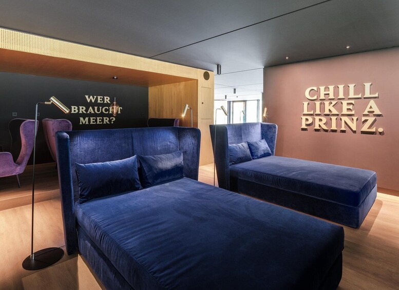 A modern lounge area with two blue sofas and a wall with the text 'CHILL LIKE A PRINZ.' 4