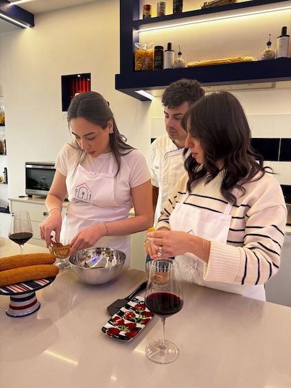Three people in a kitchen preparing food and drinks. 3