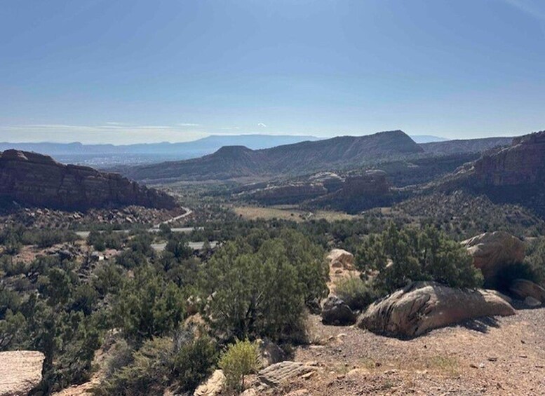A mountainous landscape with a valley, dense vegetation, and a clear sky. 5