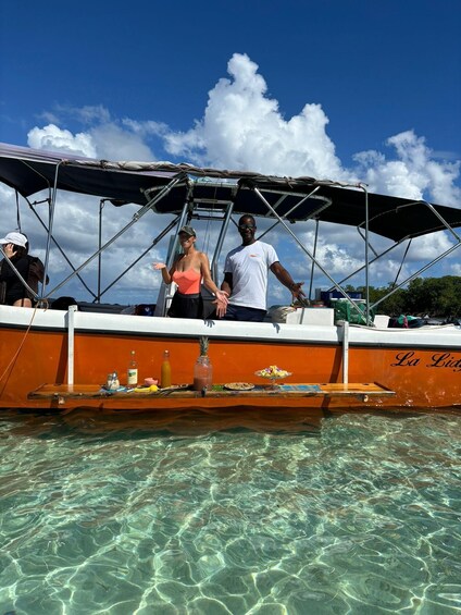 A boat with people on deck, clear water, and a blue sky with clouds. 3