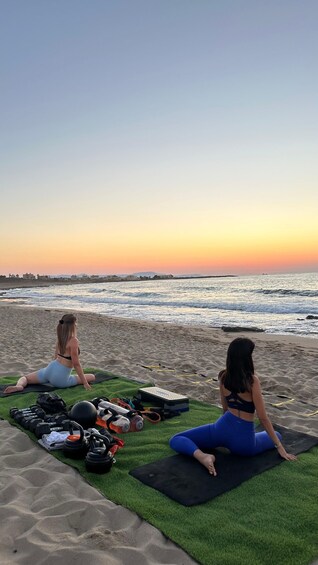 Two individuals exercising on mats at a beach during sunset. 3
