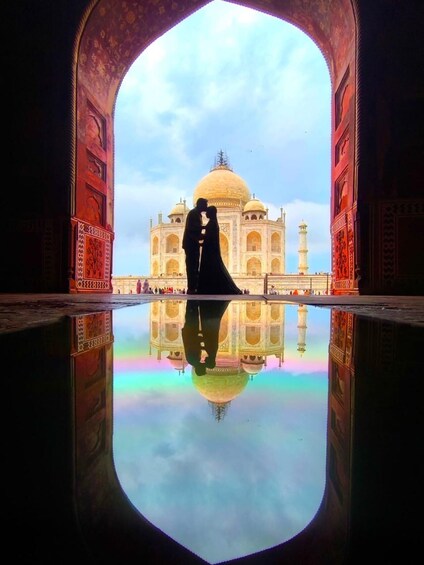 A couple embracing in front of the Taj Mahal, with its reflection visible on the water. 5