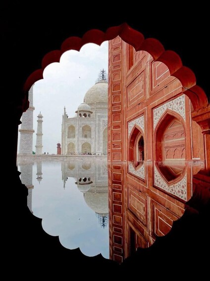 The Taj Mahal with its reflection in the water, and a red archway in the foreground. 2