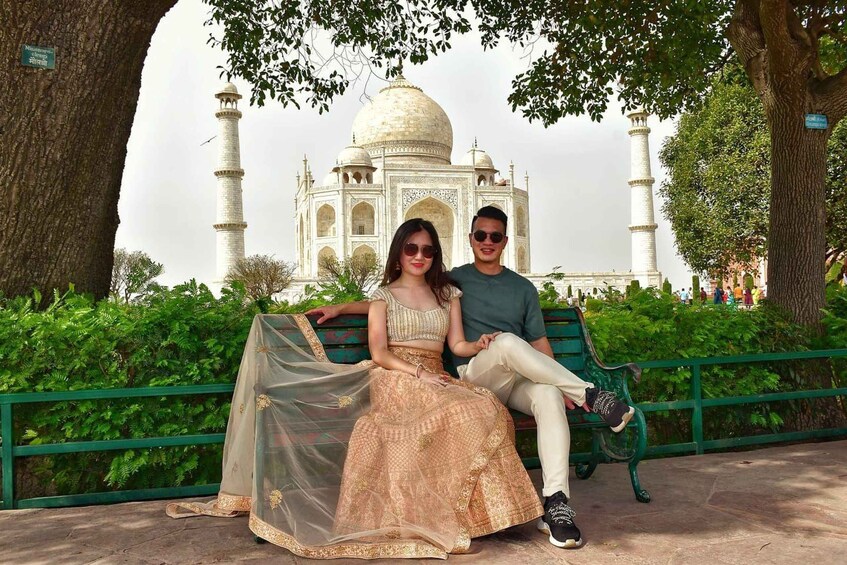 A couple sitting on a bench with the Taj Mahal in the background. 4