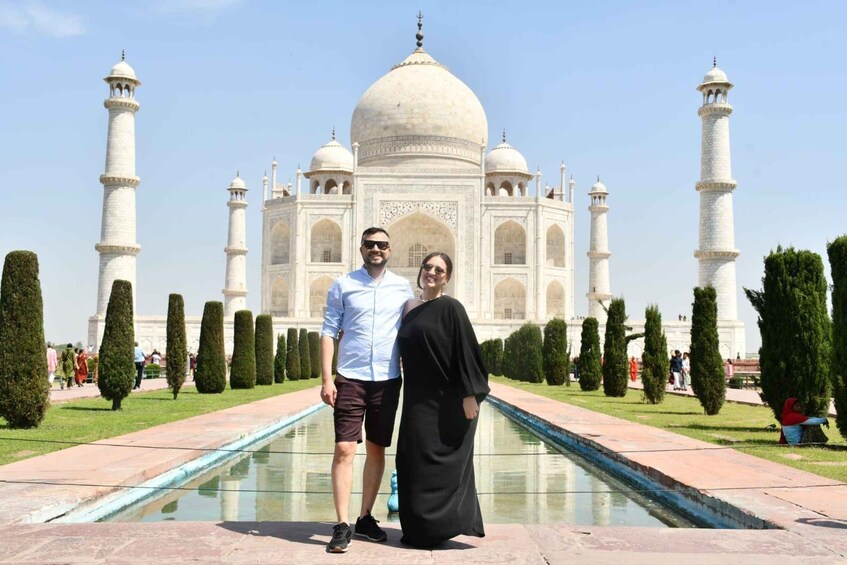 A couple standing in front of the Taj Mahal with its iconic domes and minarets. 1