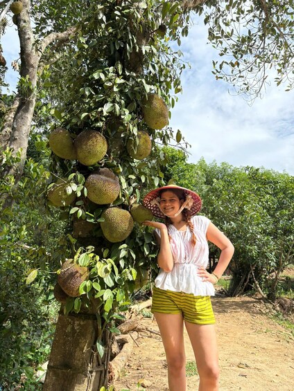 A person standing next to a durian tree with large fruit. 3